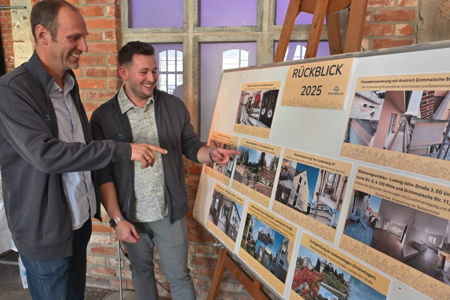 Zwei Personen zeigen auf eine Tafel mit Fotos zum Rückblick auf 2025.